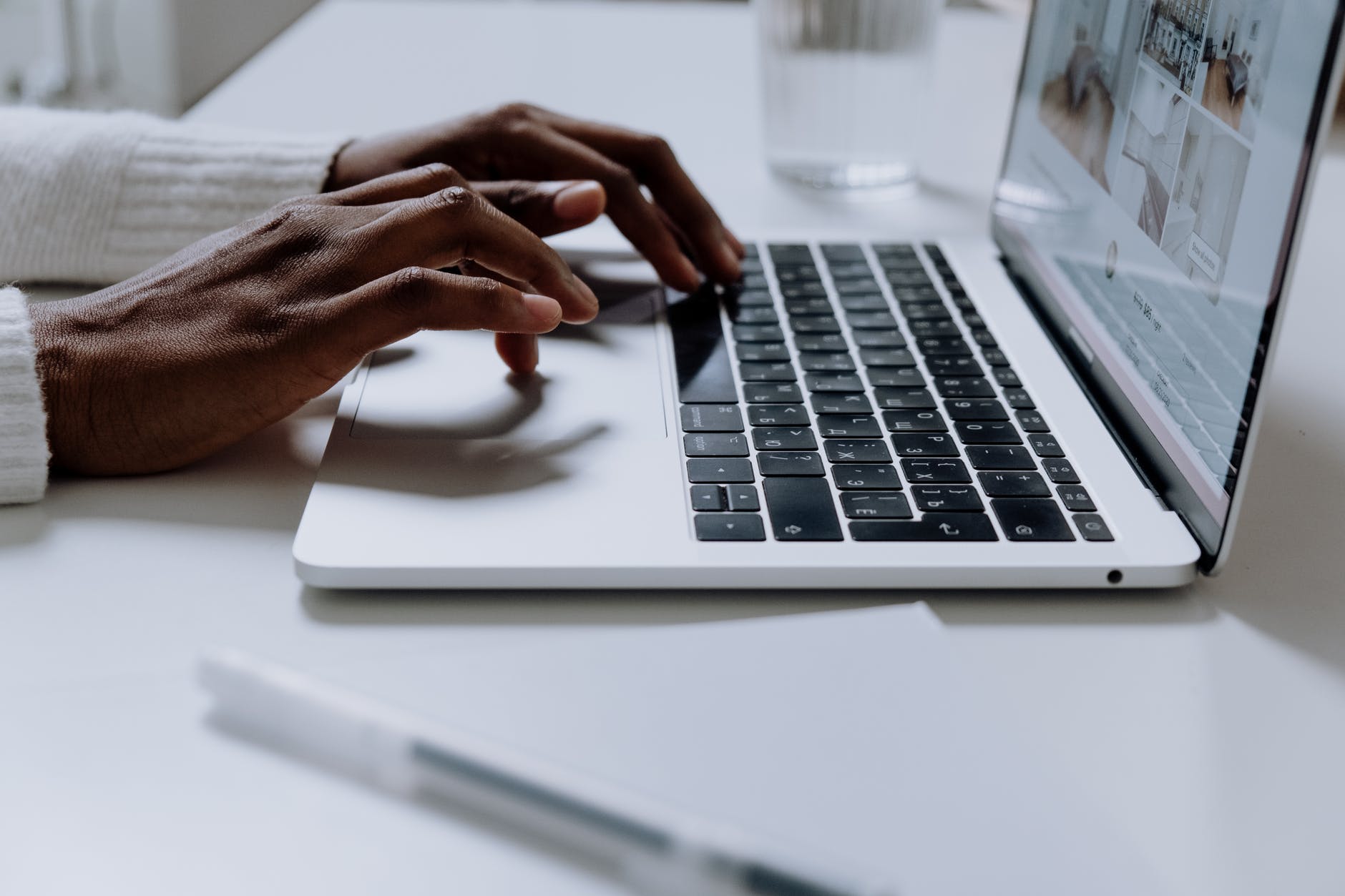 person using macbook pro on white table