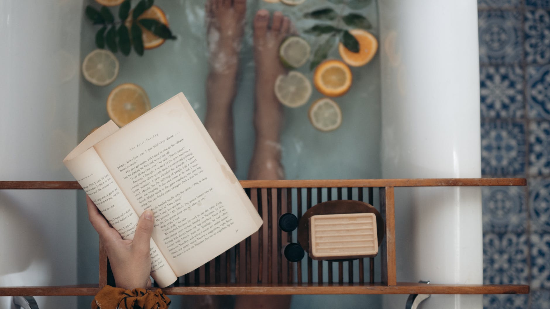 person holding book near brown wooden table