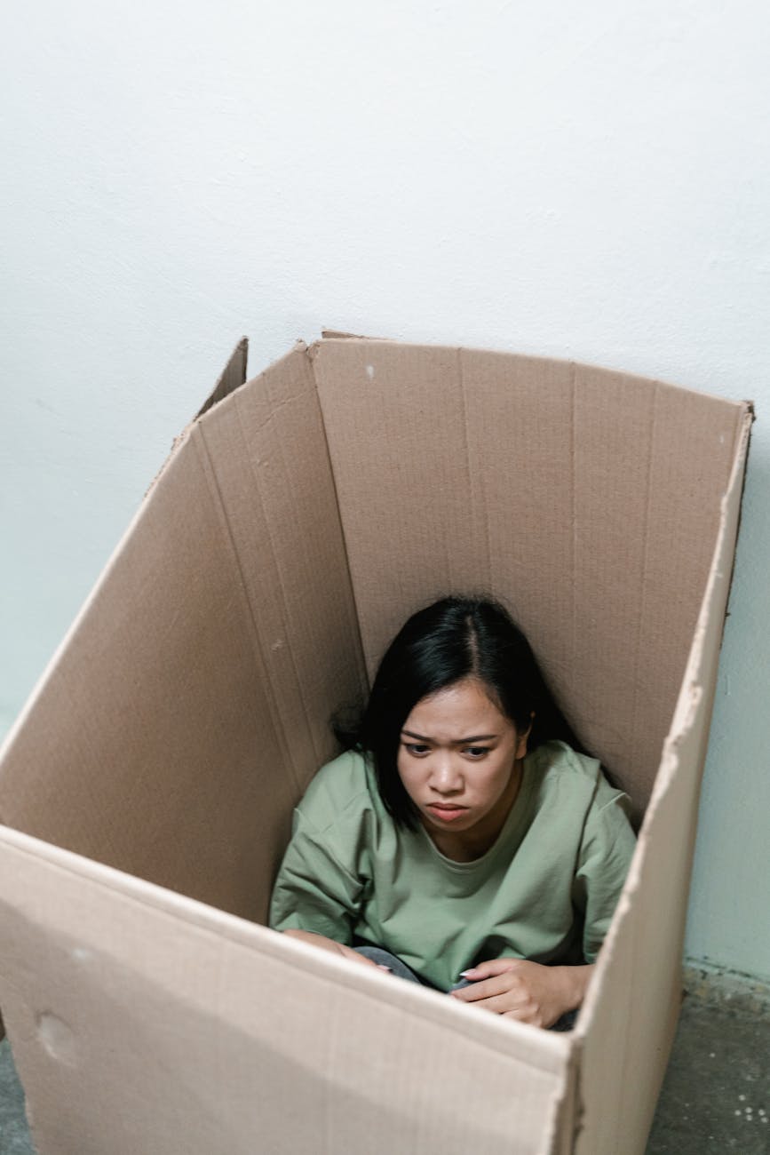 a fearful woman having claustrophobia in a cardboard box